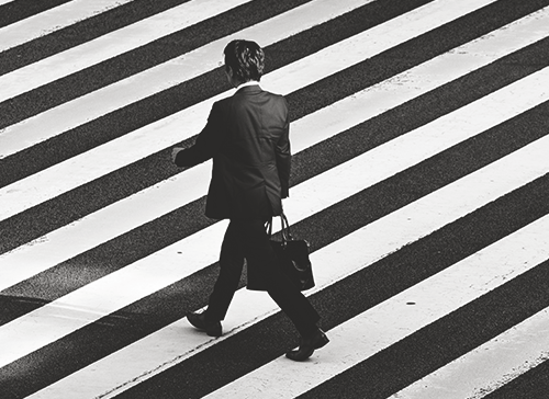 Photo of man in suite crossing the street